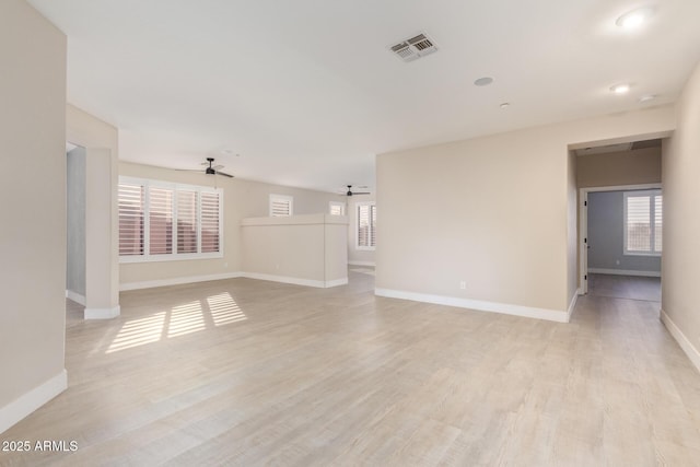 empty room with ceiling fan, light wood-type flooring, visible vents, and baseboards