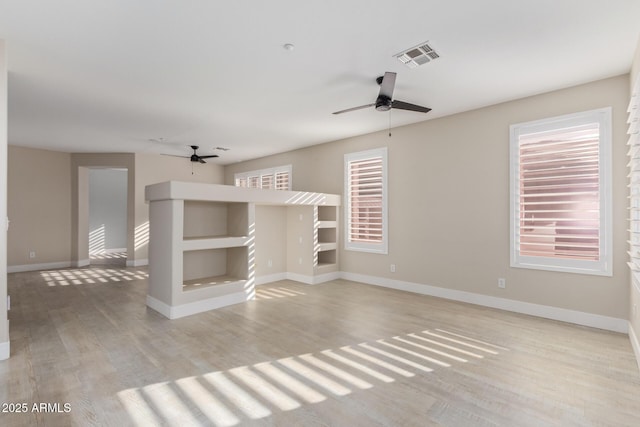 unfurnished room featuring light wood-type flooring, baseboards, visible vents, and ceiling fan