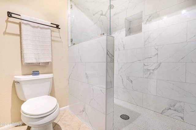 bathroom featuring toilet, tile patterned flooring, and a tile shower