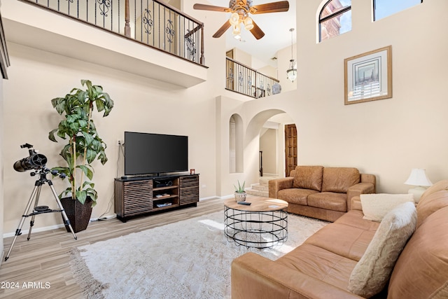 living room featuring ceiling fan, hardwood / wood-style floors, and a towering ceiling