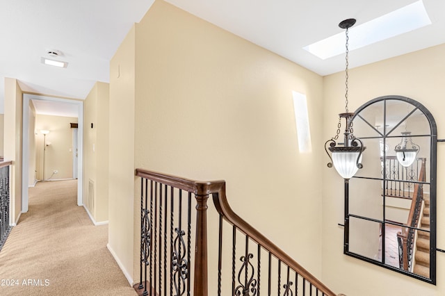 hallway with a skylight and light carpet