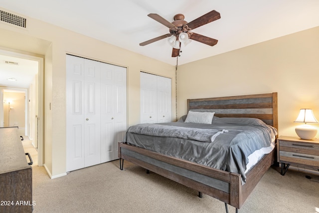 carpeted bedroom with ceiling fan and two closets