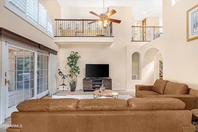 living room featuring ceiling fan, hardwood / wood-style floors, a healthy amount of sunlight, and a high ceiling