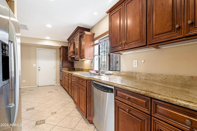 kitchen featuring light tile patterned flooring, stainless steel appliances, light stone countertops, and sink