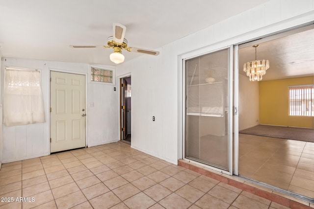 empty room featuring light tile patterned flooring, visible vents, and ceiling fan with notable chandelier
