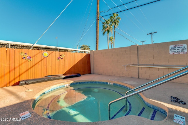 view of swimming pool featuring a community hot tub and fence