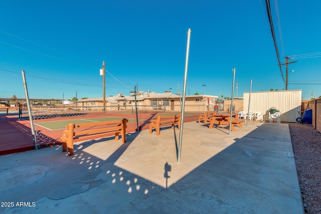 view of community with fence and a tennis court