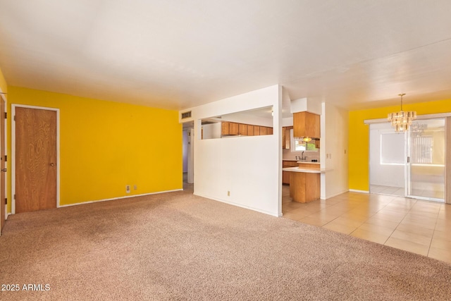 unfurnished living room featuring light colored carpet, a sink, a chandelier, and visible vents