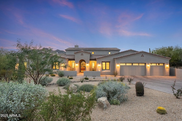 mediterranean / spanish house with stucco siding, concrete driveway, a tile roof, and a garage