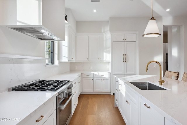 kitchen featuring high end range, light stone countertops, custom exhaust hood, a sink, and white cabinetry