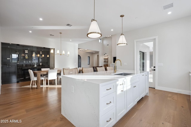 kitchen featuring white cabinetry, wood finished floors, visible vents, and a sink