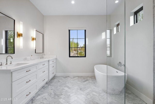 bathroom featuring double vanity, a soaking tub, baseboards, and a sink