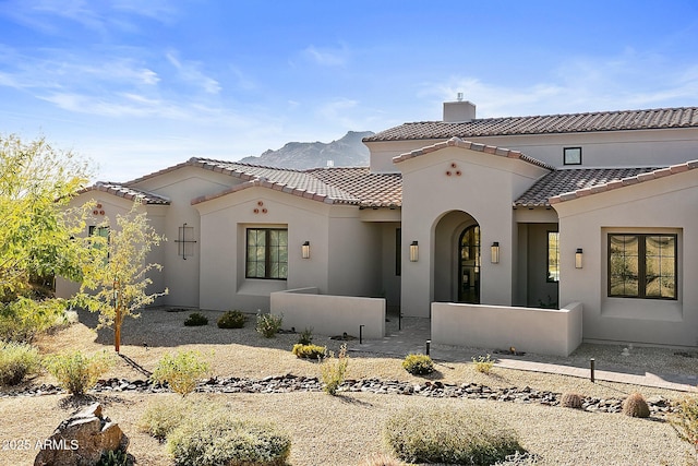 mediterranean / spanish-style home featuring a tile roof, a chimney, and stucco siding