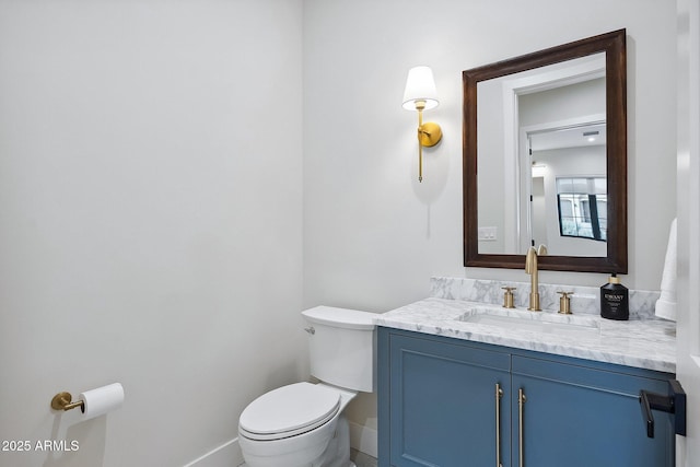 half bath featuring vanity, toilet, and baseboards