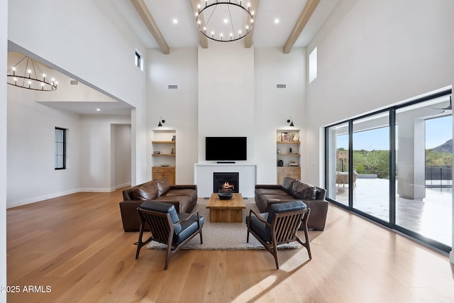 living area featuring beamed ceiling, light wood finished floors, and a chandelier