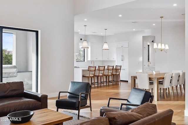 living area with a notable chandelier, recessed lighting, light wood-type flooring, and baseboards