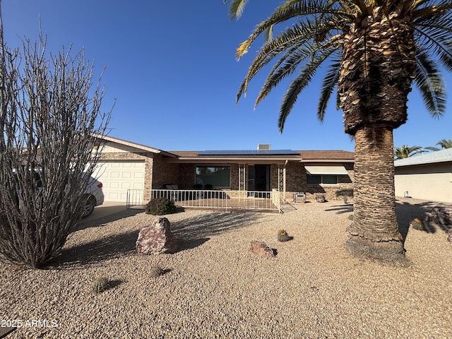 ranch-style house featuring a garage and solar panels