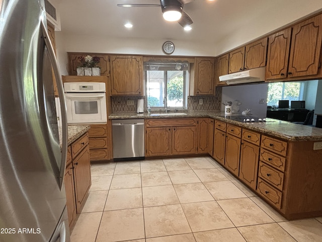 kitchen with tasteful backsplash, stainless steel appliances, light tile patterned flooring, and sink