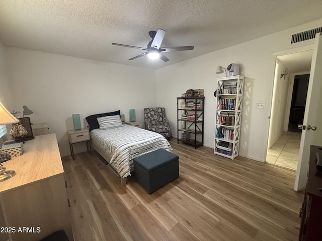 bedroom featuring ceiling fan, dark hardwood / wood-style floors, and a textured ceiling