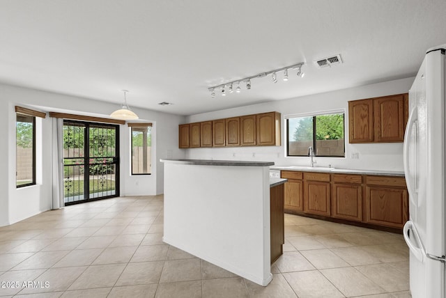 4404 W Ellis St, Laveen, AZ 85339 - kitchen featuring freestanding refrigerator, a sink, brown cabinets, light tile patterned floors, and healthy amount of natural light