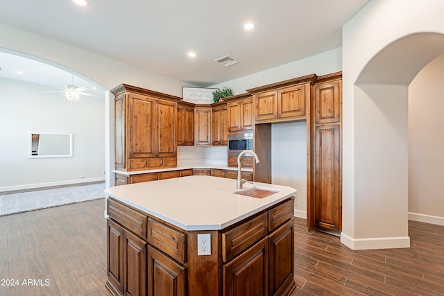 kitchen featuring ceiling fan, sink, stainless steel microwave, and an island with sink