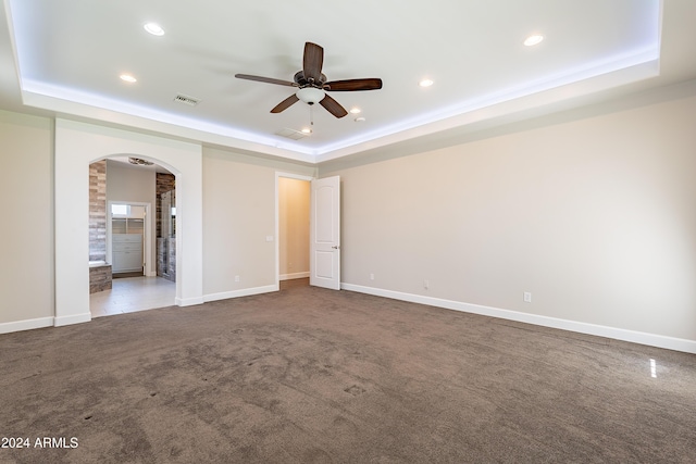 unfurnished room with carpet, a tray ceiling, and ceiling fan