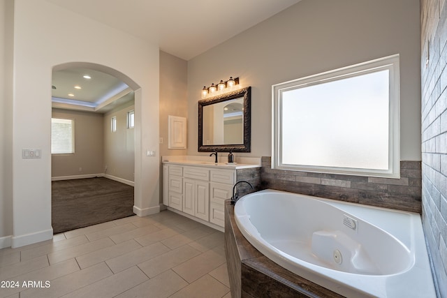 bathroom with tile patterned flooring, vanity, and tiled tub