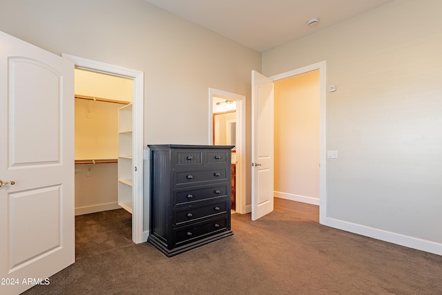 unfurnished bedroom featuring dark colored carpet, a spacious closet, and a closet