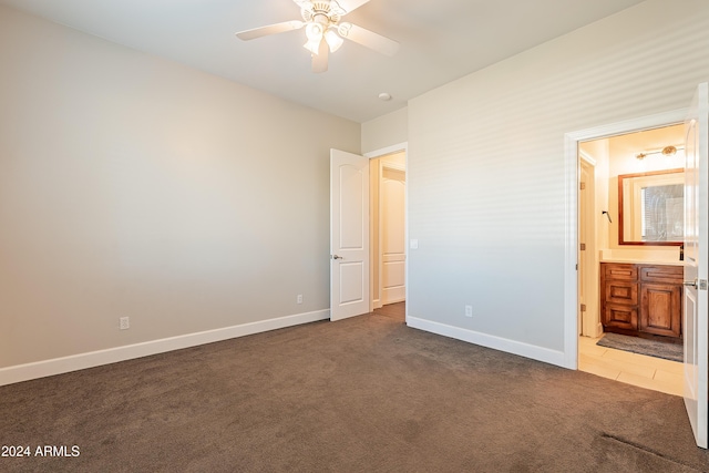 unfurnished bedroom with connected bathroom, ceiling fan, and dark carpet