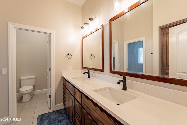 bathroom with toilet, vanity, and tile patterned floors