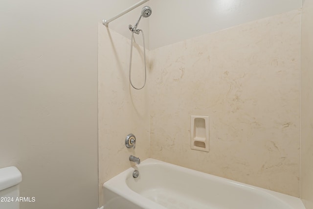 bathroom featuring toilet and tiled shower / bath