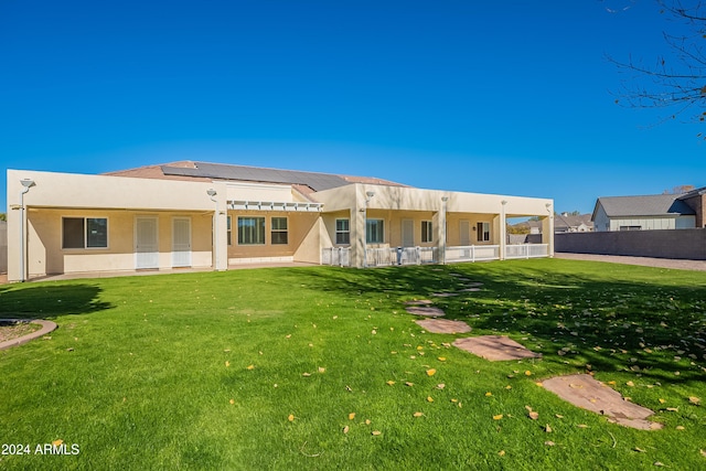 back of house featuring solar panels and a lawn