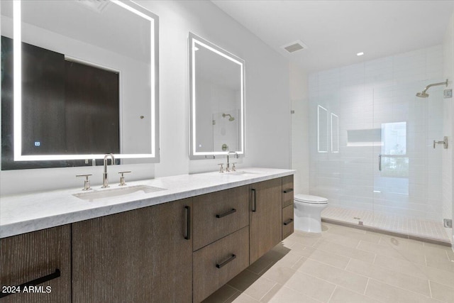 bathroom featuring toilet, vanity, tiled shower, and tile patterned floors