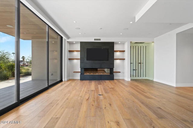 unfurnished living room with a tile fireplace, light hardwood / wood-style flooring, and floor to ceiling windows