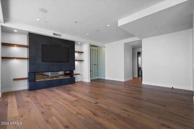 unfurnished living room featuring a tiled fireplace and hardwood / wood-style floors