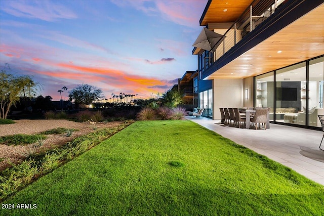 yard at dusk featuring a patio