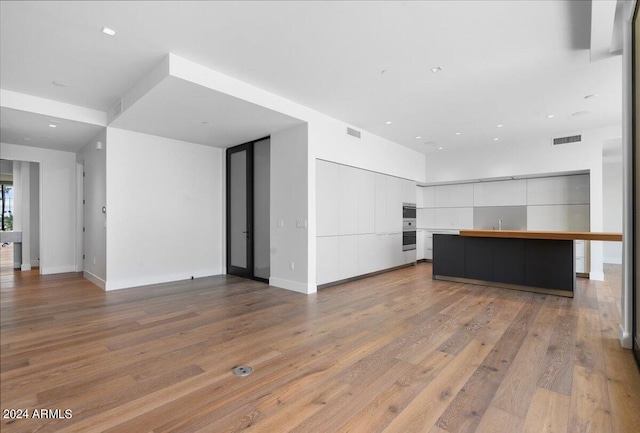 unfurnished living room with light hardwood / wood-style flooring and sink