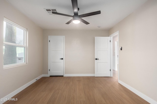 unfurnished bedroom with light wood finished floors, visible vents, a ceiling fan, and baseboards