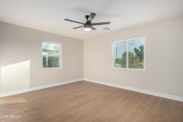 empty room featuring light wood finished floors, visible vents, ceiling fan, and baseboards