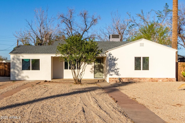 ranch-style house featuring stucco siding, fence, a chimney, and a shingled roof