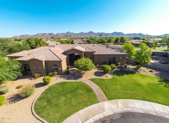view of front of property featuring a tile roof, a mountain view, a front yard, and stucco siding