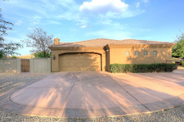 mediterranean / spanish-style house featuring stucco siding, a tile roof, a gate, an attached garage, and driveway
