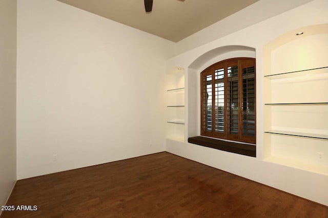 interior space with arched walkways, built in shelves, a ceiling fan, and wood finished floors