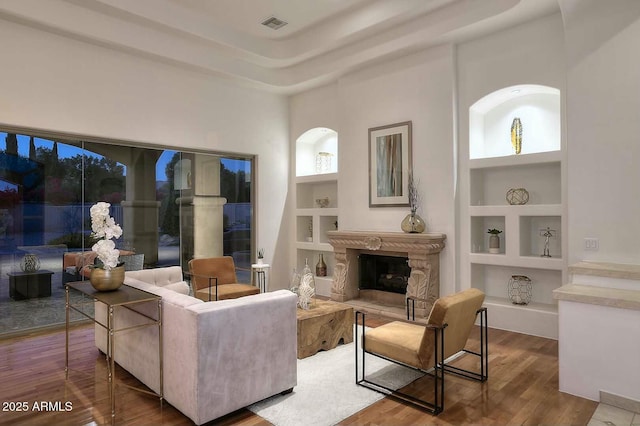 living room with visible vents, built in shelves, wood finished floors, and a fireplace