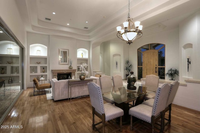 dining area with arched walkways, built in features, hardwood / wood-style floors, and a notable chandelier