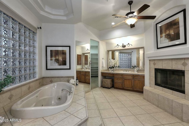 bathroom with a ceiling fan, a whirlpool tub, vanity, tile patterned floors, and a tile fireplace