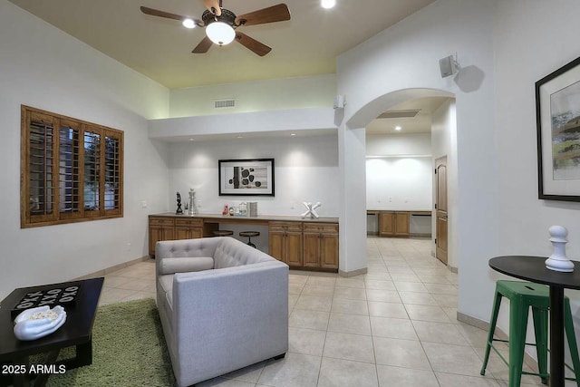 living area with indoor wet bar, light tile patterned floors, visible vents, ceiling fan, and arched walkways