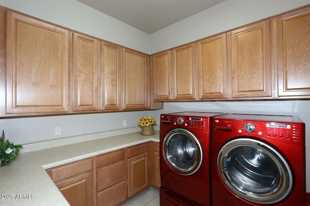 washroom with light tile patterned floors, washer and clothes dryer, and cabinet space