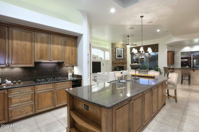 kitchen featuring tasteful backsplash, open floor plan, light tile patterned floors, gas cooktop, and a sink