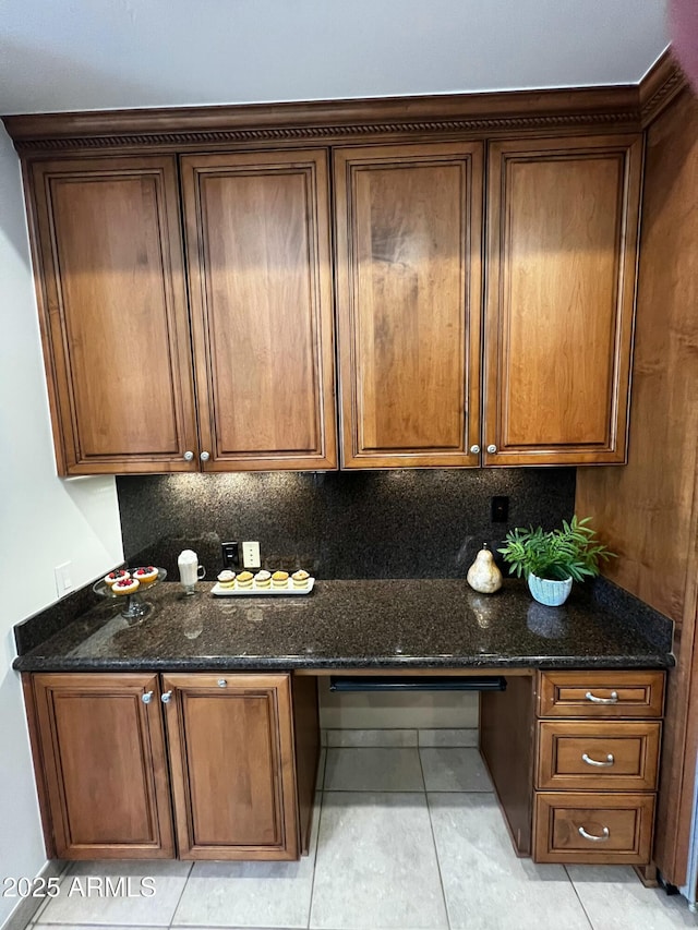 kitchen featuring dark stone countertops, built in desk, and decorative backsplash